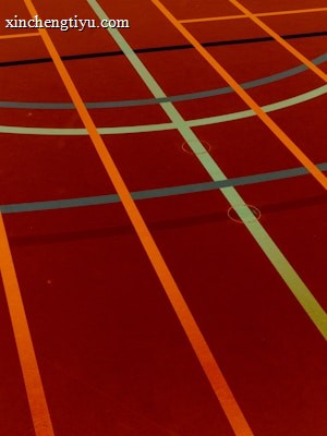 A sports court with intersecting lines in orange and blue, creating geometric patterns on a reddish-brown surface.